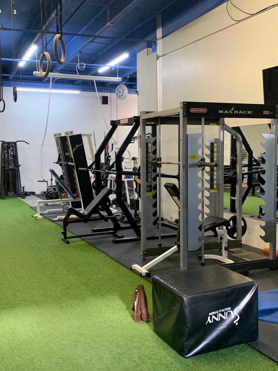 CNE's functional training area: MaxRack, benches, hanging rings, plyo box, and turf lane